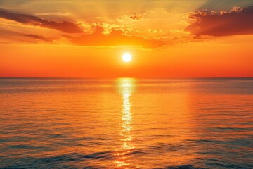 Obraz premium Dramatic sunset over the ocean with glowing clouds reflecting in the water.