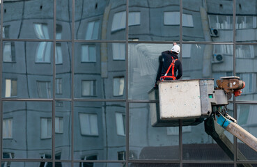 A man on a lift washes mirrored windows of a multi-story building.