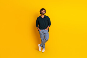 Fototapeta premium Confident young man in casual attire stands against vibrant yellow backdrop, embodying style and positivity