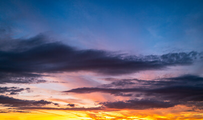 Sunset background. Dramatic majestic scenery sunset. Sky with clouds in sunset sky light background. Sunrise with clouds in various shapes. Calm sunset sky and sun through clouds over.