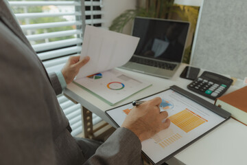 Typical office work atmosphere for company employees. A businessman is diligently handling important documents in his personal office. Important project report documents are being analyzed by experts.