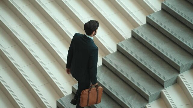 Top view of smart business man walking up stairs with bag in the hand. Professional project manager climb up the stair and going to workplace. Increasing skill, getting promotion, traveling. Exultant.