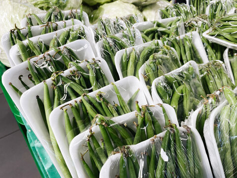 Green beans packaged with styrofoam and plastic displayed in supermarket