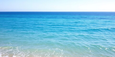 Obraz premium A serene image of a vast ocean, with clear blue water stretching out to the horizon under a clear sky and gentle waves lapping at the shore, nature, water