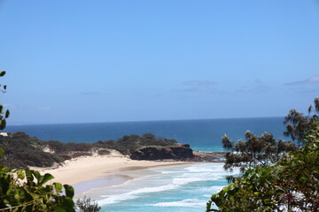 Naklejka premium blue sky, deep blue sea, forested shores and sandy beach