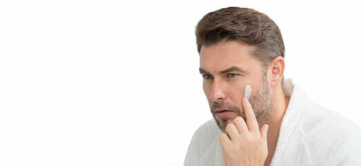 Fototapeta premium American man applying face cream on wrinkle. Morning beauty routine. Man with wrinkle skin. Anti-aging and wrinkle cream. Concept of male beauty. White isolated banner with copy space.