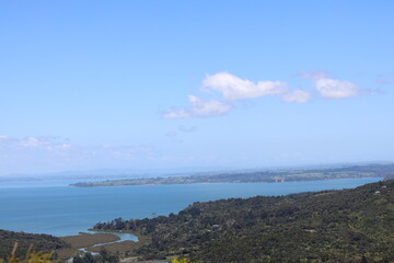 Obraz premium blue ocean bays and green forested lands under blue sky and fluffy white clouds