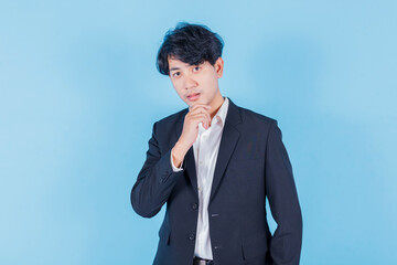 portrait of young handsome southeast Asian millenial businessman on blue background