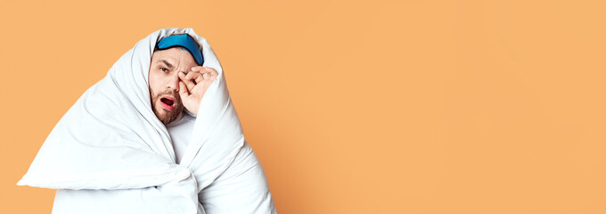 Good morning. Guy wakes up, yawns and rubs his eyes wrapped in blanket