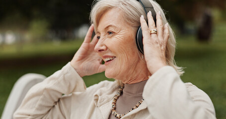 Senior woman, headphones and relax with music at park for audio streaming, podcast or radio in...