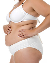 Plus size woman's hand holding excessive belly fat in white swimsuit on isolated white background, Clipping path