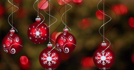 Image of red christmas baubles and fairy lights flickering in background