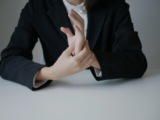 Asian businesswoman massaging her palm in pain caused by working on a computer keyboard for a long...