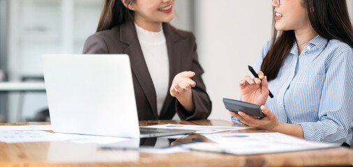 Two brunette business woman discussing, talking, advising each other at desk office.