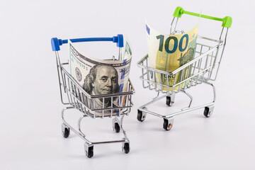 100 US dollar and 100 euro bills in a miniature shopping cart from a supermarket