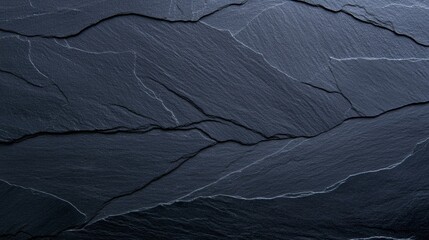 A close-up of dark slate stone, showcasing its textured surface with fine lines and natural patterns.