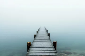 Foto op Canvas Wooden pier disappearing into dense fog over a still lake. © Abdul