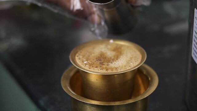 slow motion Closeup of man's hand placing hot steaming  south Indian filter coffee on the table.