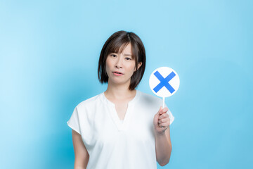 バツ印のプレートを持つ女性