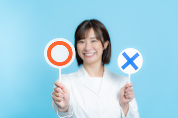 白衣を着て丸バツプレートを持つ女性