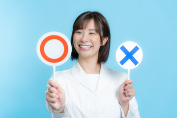 白衣を着て丸バツプレートを持つ女性