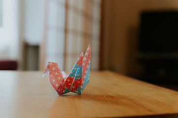 blue red and white origami, tsuru bird paper art on wooden table, japanese style decoration