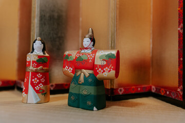 red and green chinese new year decorations, male and female wooden dolls placing in front of a golden background, traditional Japanese culture, kimonos with vibrant colors