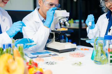 Fototapeta premium Team of scientists examining food samples in a lab with microscopes. Perfect for themes of food science, biotechnology,