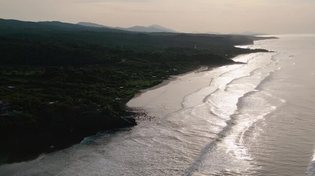 El Salvador beach aerial view of secluded surf spot of El Cuco called Punta Mango with small beach houses and tranquil ocean setting and chiaroscuro contrast