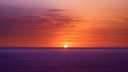 Fototapeta premium Stunning Sunset Over the Calm Ocean, Showcasing Vibrant Orange and Purple Hues in the Evening Sky