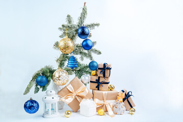 Christmas toys on the Christmas tree. Space for text. Christmas gifts in craft paper with a blue bow. Eco friendly trendy zero waste packaging, holiday mood concept, making gifts. 