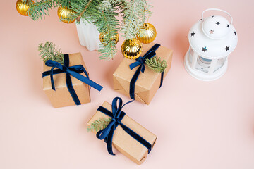 Christmas gifts in craft paper with a blue bow. Christmas tree with golden balls. Eco style. 