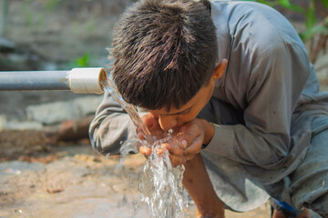 Rural Innocence: Boy Quenching Thirst from a Fresh Water Source © Ali Magsi