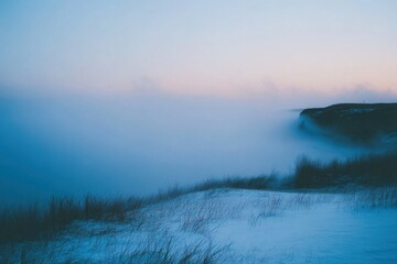 A misty landscape with a cliff at sunrise.