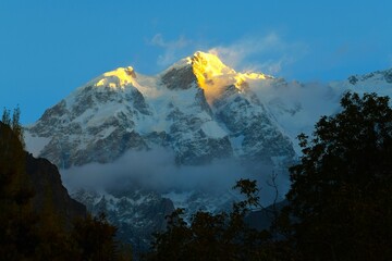 First sun's rays touching the summit of Ultar Peak (7388 m, also Ultar Sar, Bojohagur Duanasir II)...