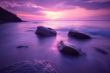 Naklejka premium A peaceful seascape with rocks in the foreground and a purple sunrise in the background.