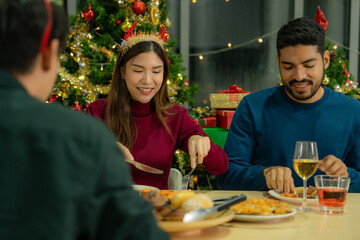 Group of Asian friends enjoying Christmas party for new year celebrate. Friends having fun together at home. men and women opening box gift and present together at home with Christmas tree.