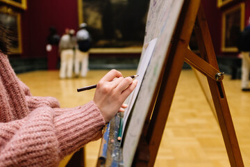 Obraz premium Woman artist sketching with pencil on canvas in art museum