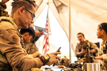 A group of military men in combat gear patrol in the middle of a desert and tropical jungle. Soldiers in full combat gear in dry weather conditions assemble and march on a mission.