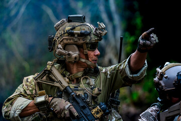 A group of military men in combat gear patrol in the middle of a desert and tropical jungle....