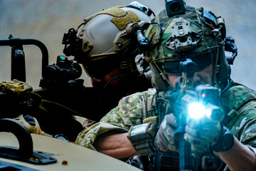 A group of military men in combat gear patrol in the middle of a desert and tropical jungle. Soldiers in full combat gear in dry weather conditions assemble and march on a mission.