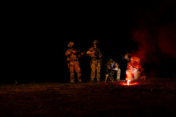 Obraz premium A group of military men in combat gear patrol in the middle of a desert and tropical jungle. Soldiers in full combat gear in dry weather conditions assemble and march on a mission.
