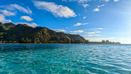 Obraz premium Scenic view of idyllic crystal clear turquoise ocean water and rugged mountainous forest covered tropical island of Moorea in French Polynesia, South Pacific