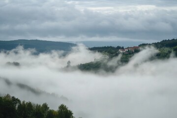 Obraz premium A small village nestled in a valley, shrouded in fog.