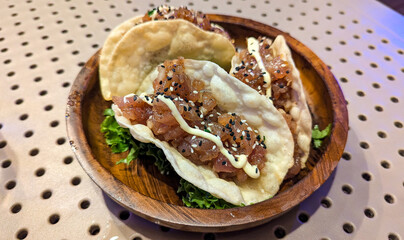 Delicious cuisine of raw tuna poke taco served on a wooden plate on tropical island of Mo'orea in French Polynesia, South Pacific