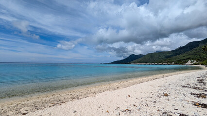 Scenic view of white sandy beach and crystal clear turquoise ocean water on coastline of tropical island of Moorea in French Polynesia, South Pacific