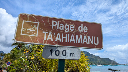 Fototapeta premium Close up of Plage de Ta'ahiamanu beach sign on tropical island of Moorea in French Polynesia, South Pacific
