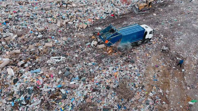 Garbage truck collects waste at busy landfill site during afternoon hours