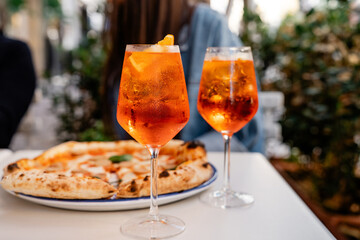 Elegant dining experience featuring two refreshing Aperol Spritz cocktails served in wine glasses,...
