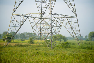 Electricity transmission tower, High-voltage pylon in field, Steel structure in green farmland, Power line tower in rural area, Transmission tower in agriculture field stock photo.